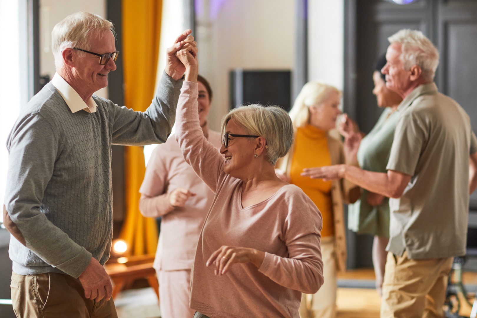 Seniors dancing together in a community room at a California adult day health care center